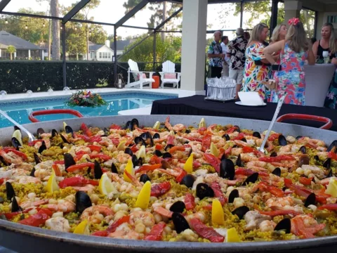 Pan of seafood paella beside a screened pool at a party
