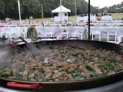 Paella cooking at a large tented outdoor reception