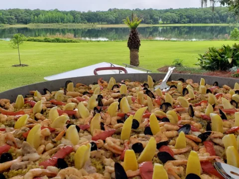 Seafood paella cooking on a lawn overlooking a lake