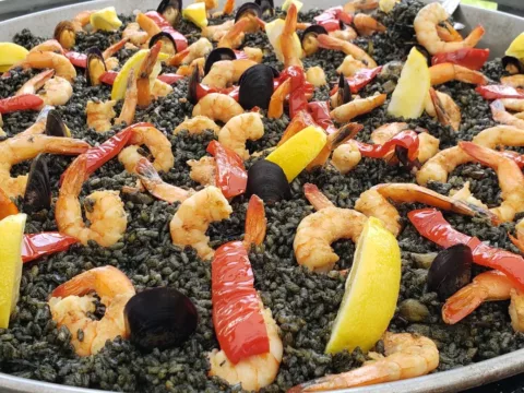 Black paella with shrimp, lemon and red peppers