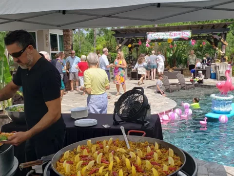 Chef cooking paella by the pool at a flamingo-themed party